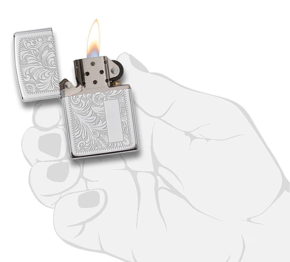 Widok z przodu zapalniczka Zippo High Polish Chrome ze wzorem weneckim i płytką na inicjały otwarta z płomieniem w stylizowanej dłoni