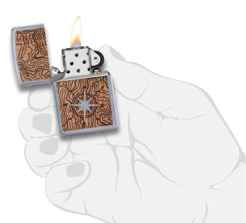 Zapalniczka Zippo Woodchuck mapa z kompasem otwarta z płomieniem w stylizowanej dłoni